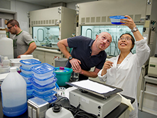 man and woman in lab looking at sample in plastic container