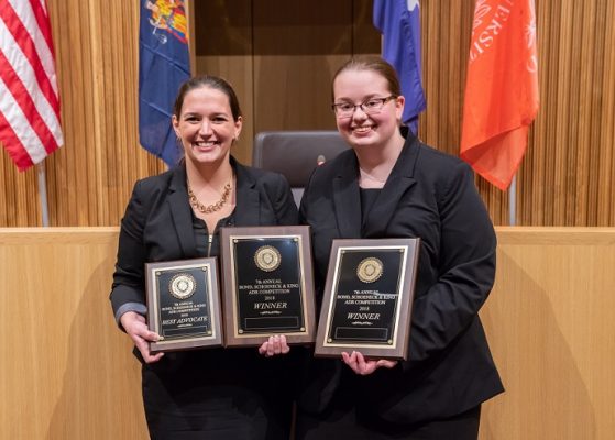 two women standing holding plaques