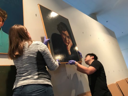 Students hang Robert Shetterly's portrait of Dorothea Lange.