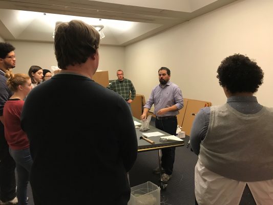 Andrew Saluti, assistant professor and program coordinator in the museum studies graduate program, instructs museum studies students on the hanging of the exhibition.