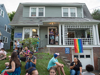 Exterior photo of 750 Ostrom Ave. showing students gathered on the lawn.