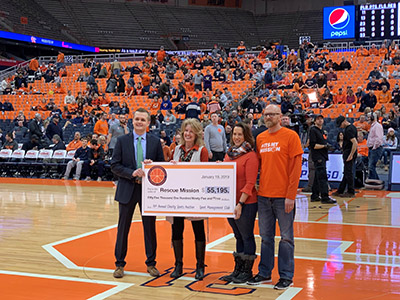 SPM Club vice president Connor Monzo (left) and longtime SPM Club co-advisor Kate Veley (second from left) present a check for $55,195 to representatives from the Syracuse Rescue Mission on Jan. 18 at the Carrier Dome.