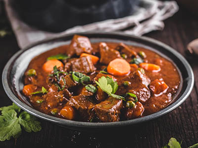 Beef stew with carrots, food photography, lot of herbs inside stew