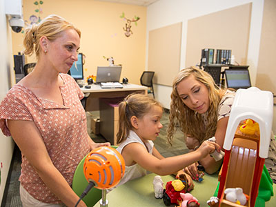 Two adults and a young girl playing in the Communications Sciences and Disorders Research Lab