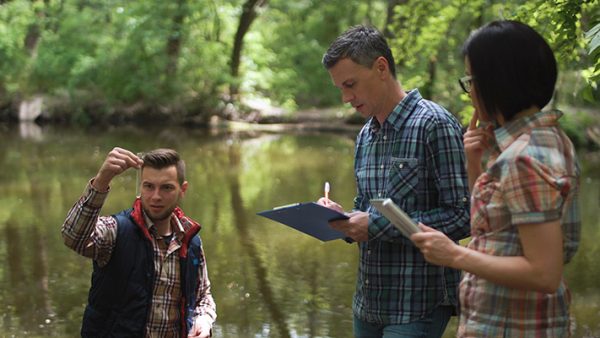 three people standing near lake