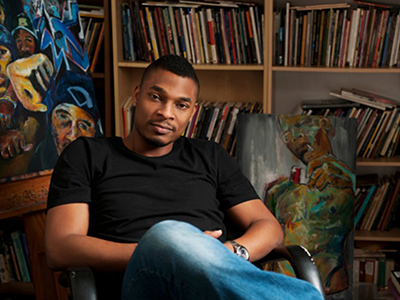 Poet Terrance Hayes sitting in front of a bookshelf.