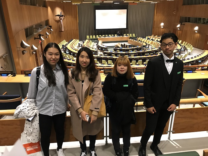 four people standing in front of large auditorium of United Nations
