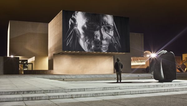 man looking at video projected on side of Everson Museum