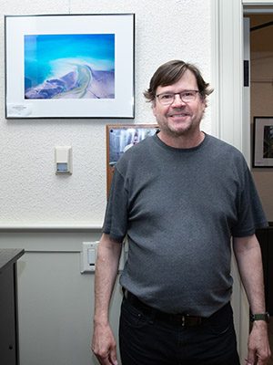 Man standing in front of photo mounted on a wall