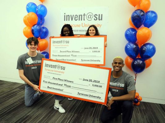 four people holding two oversized checks