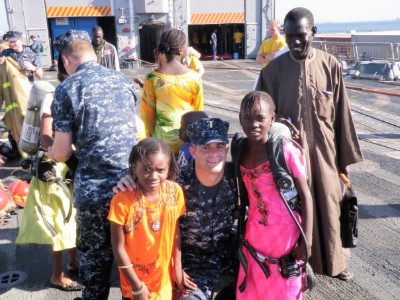 Sailor on deck of ship with African migrants