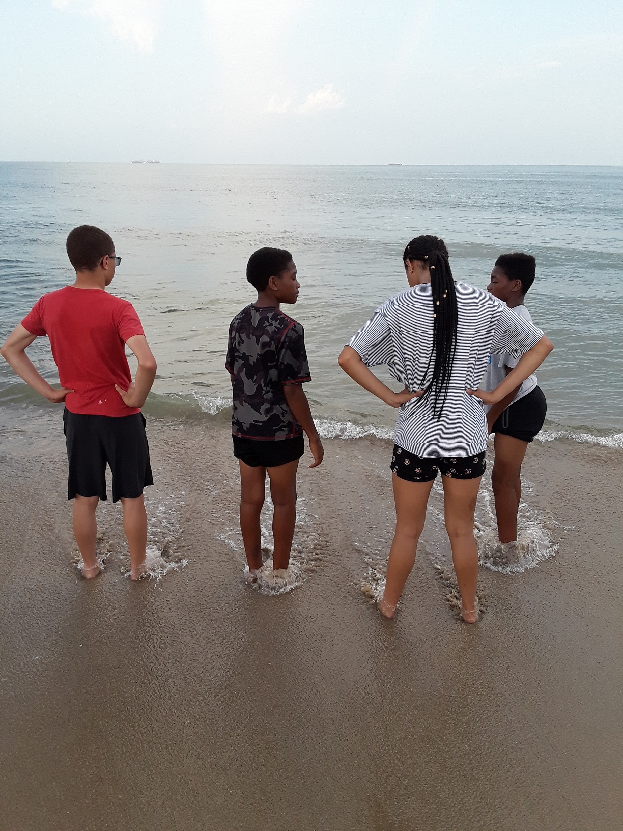 four people standing on beach