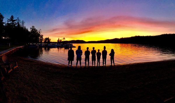 group of children at water's edge at sunset