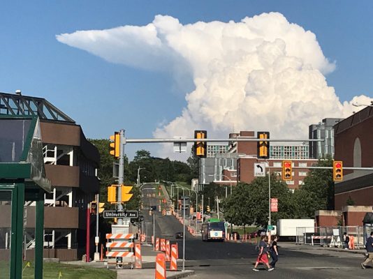 large cloud formation over city street and buildings