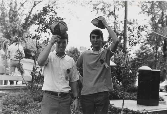 Two male students holding hats.