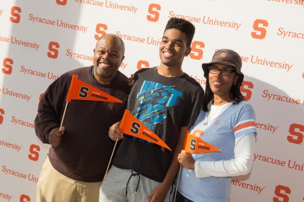 three people in front of Syracuse University backdrop