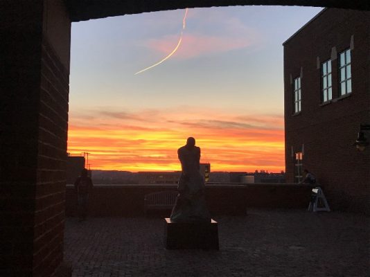 sunset beyond building and statue