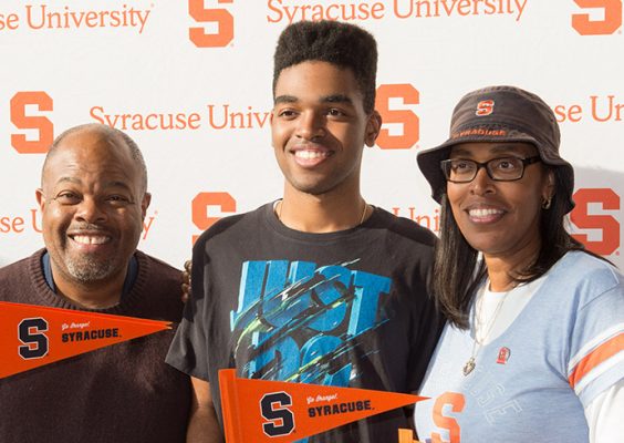 student with parents in front of Syracuse University backdrop