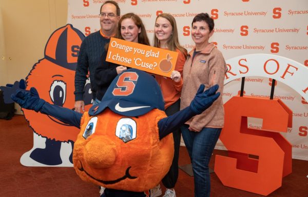 family poses with Otto in front of Syracuse University backdrop