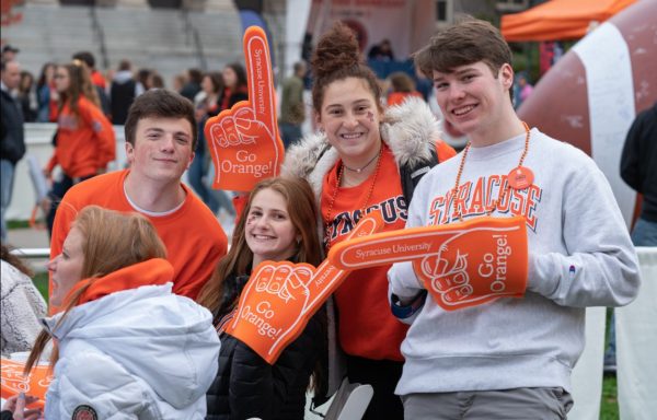 group of four with orange foam fingers at football tailgate