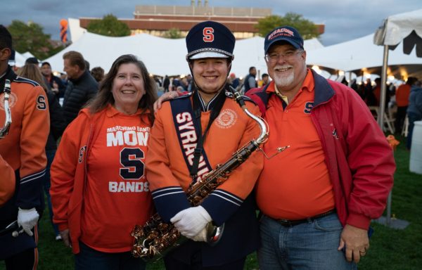 two parents pose with marching band saxophonist