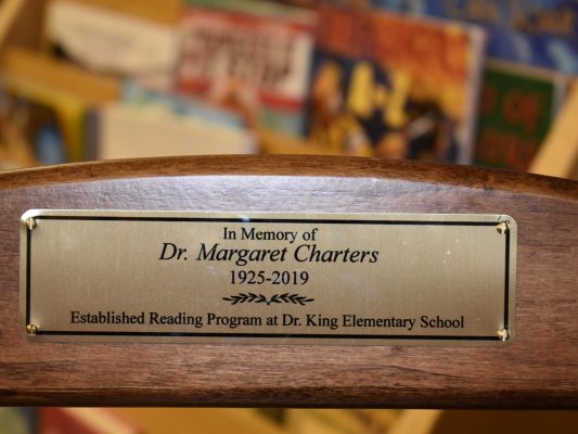A closeup of a plaque which reads, "In memory of Dr. Margaret Charters 1925-2019. Established Reading Program at Dr. King Elementary School."