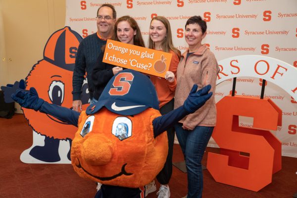 family with Otto has their photo taken holding Orange you glad I chose 'Cuse? sign