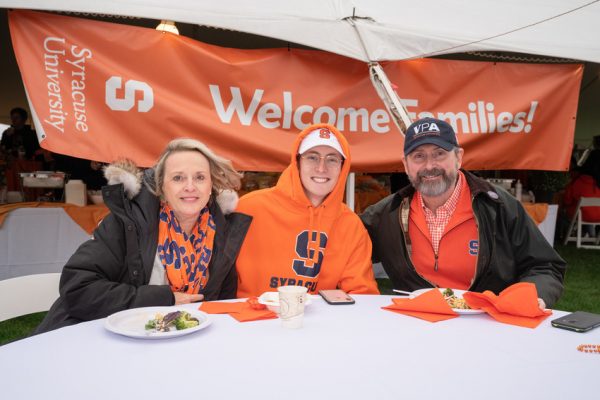 three people at a table in front of Welcome Families banner