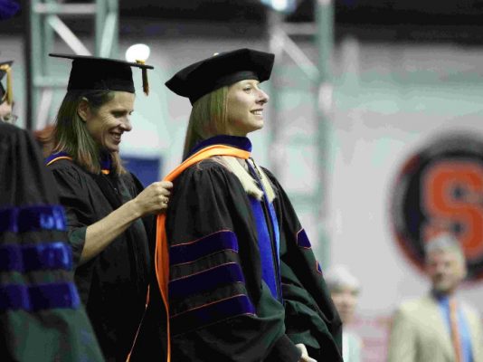 woman putting graduation sash around a woman