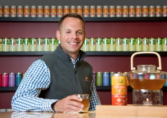 Man drinking tea in front of wall of tea.