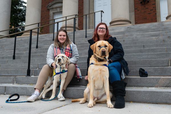 two women sitting with two dogs on steps of Hendricks Chapel