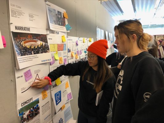 students looking at papers on a display board