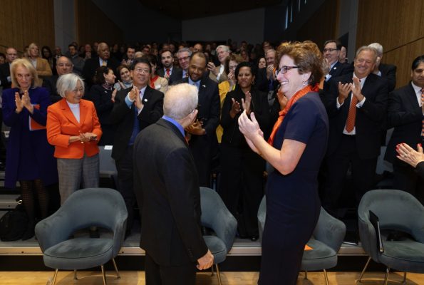 man and woman standing in front of applauding crowd.