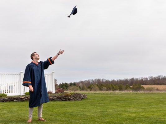 person throwing graduation cap in air