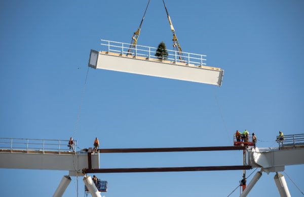 steel beam being lowered into stadium roof crown-truss