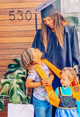 person in graduation gown with two children