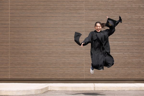person in graduation gown jumpin