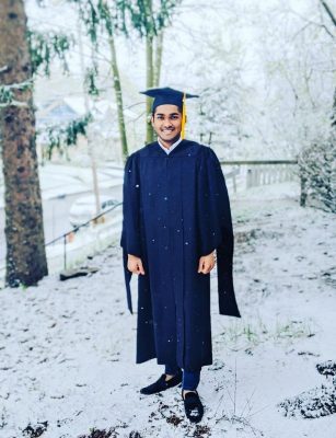 person in graduation gown on snowy yard