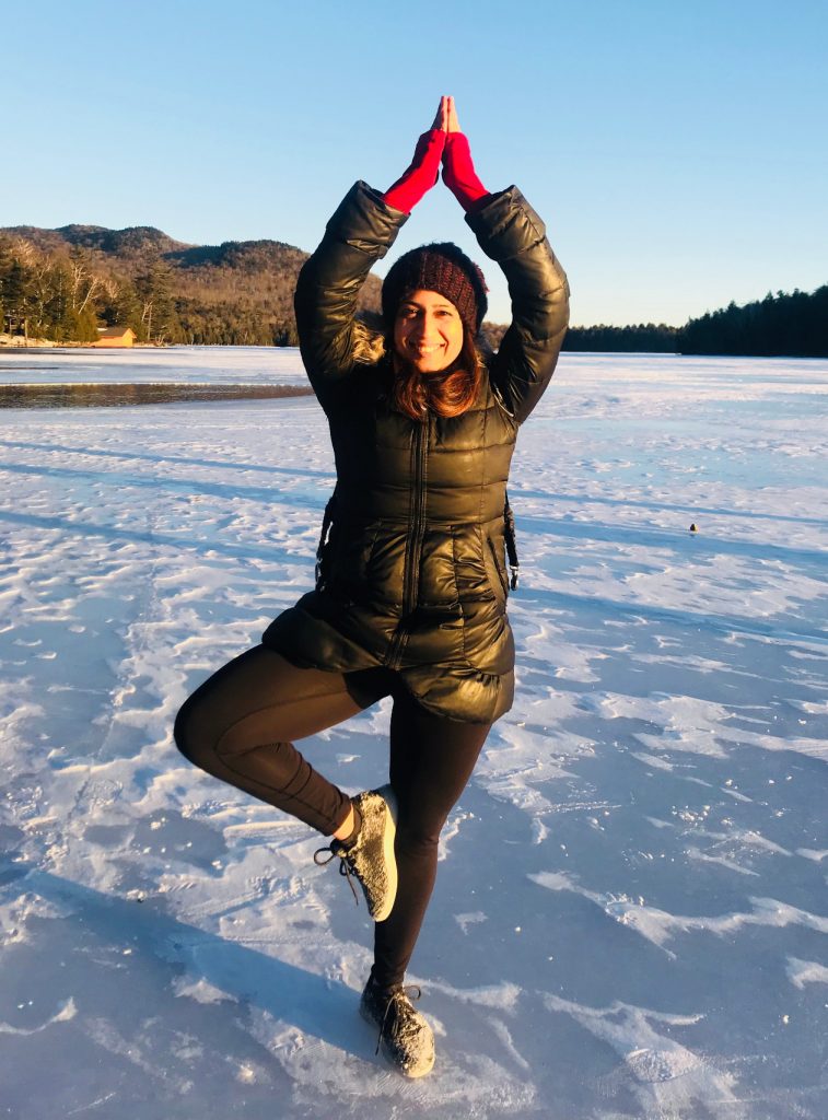 person standing on snow doing yoga pose