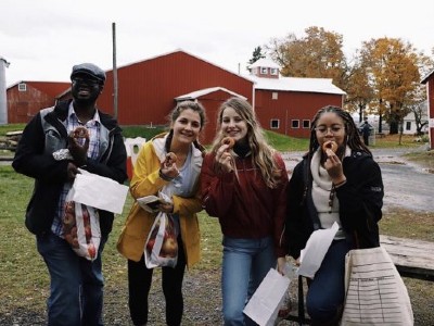 Four students stand together outside holding donuts