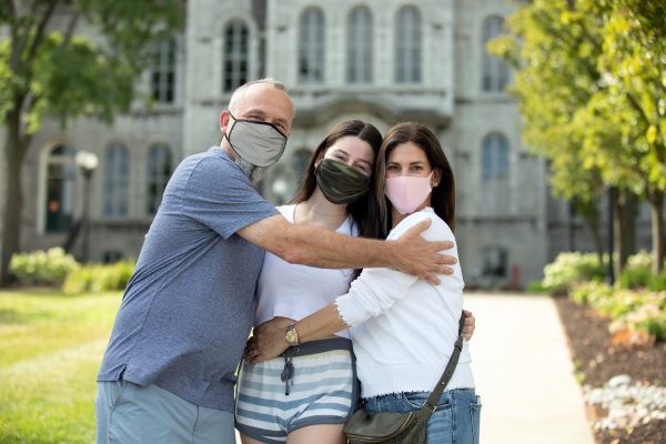 three people with masks hugging