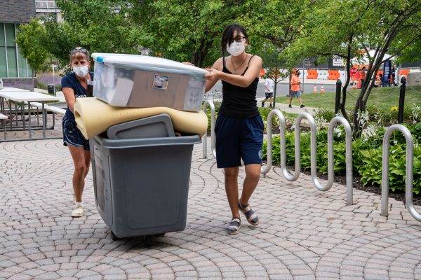 two people pushing bin with belongings