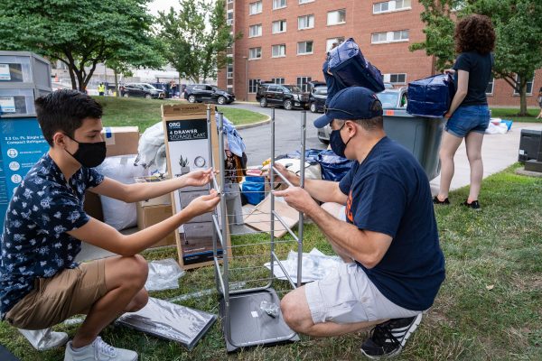two people with masks putting together stand