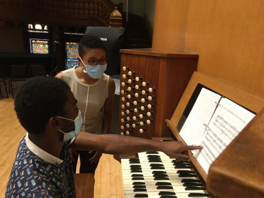 person playing organ while another person watches