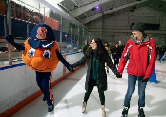 Otto mascot and two students holding hands on ice skating rink