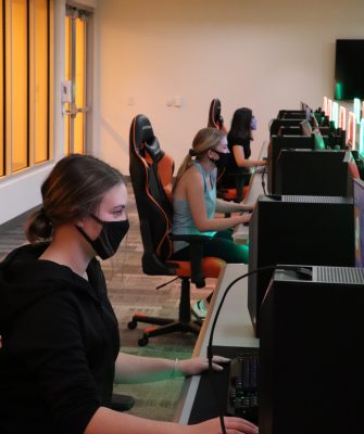 people wearing masks sitting at computers