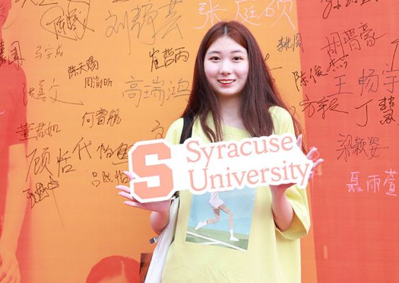 SU student in China posting with a Syracuse University sign