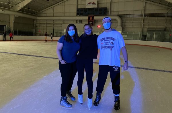 Three students posing on the ice at the Tennity Ice Skating Pavilion.