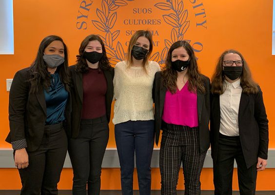 Five students standing in front of wall with SU seal
