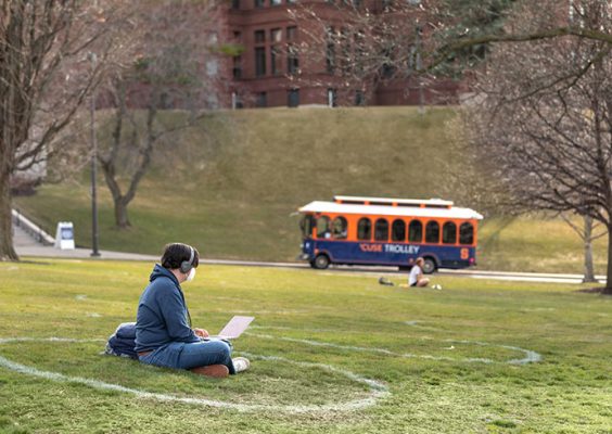 student sitting on campus lawn